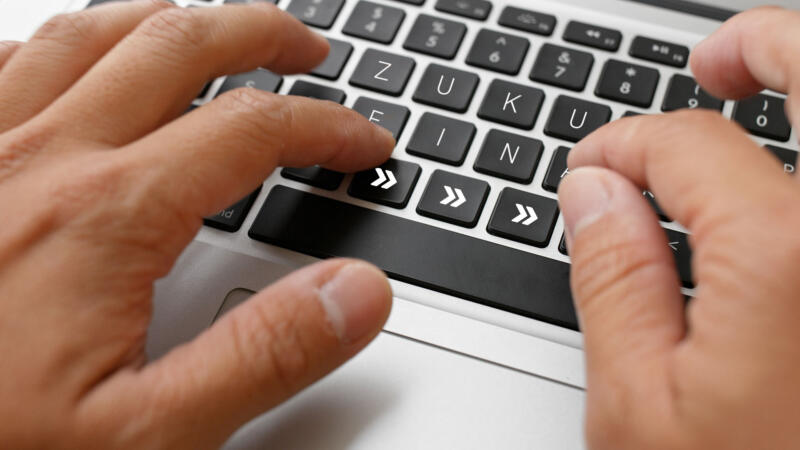 Eine Person tippt auf einer Tastatur von einem Laptop