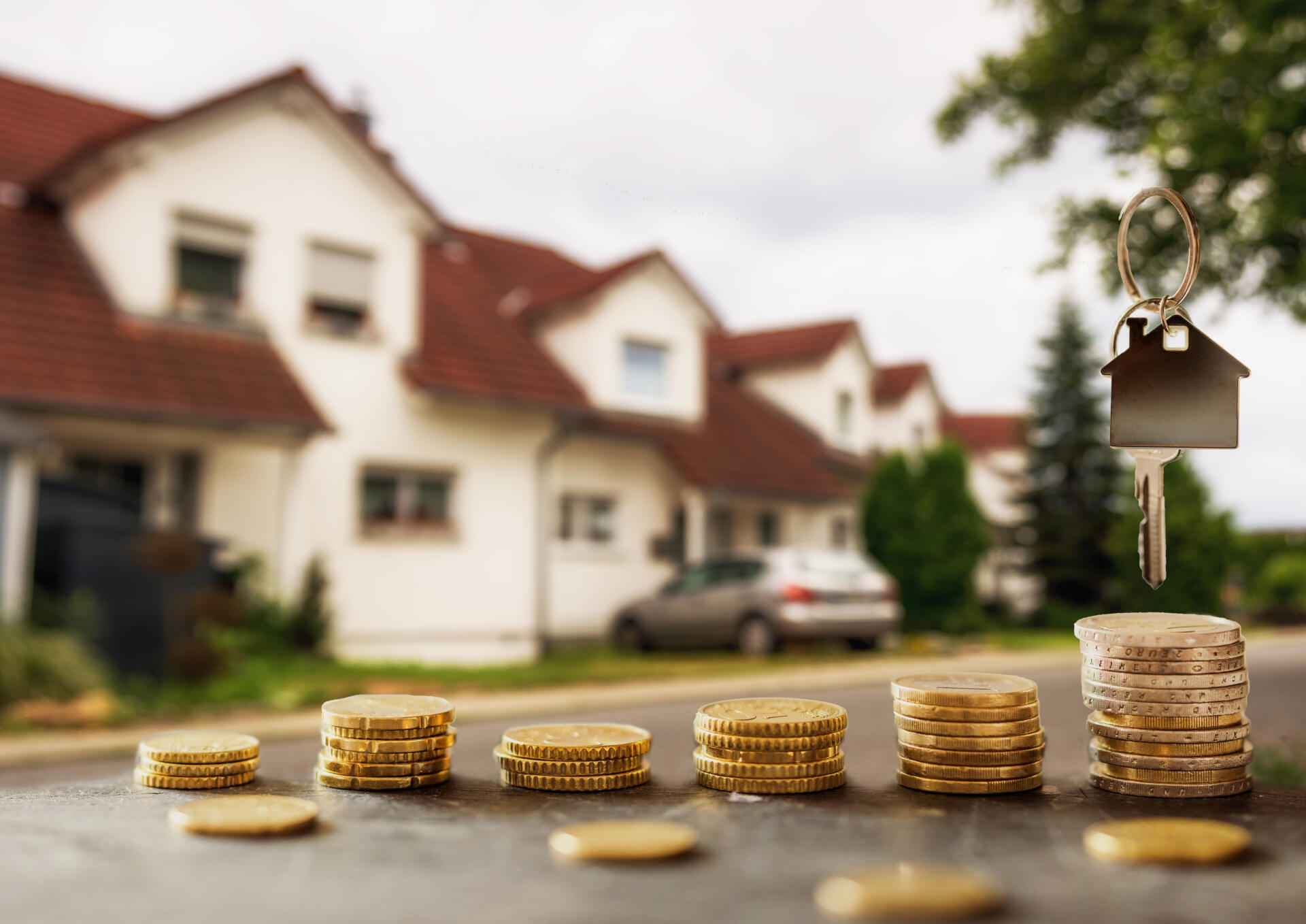 Mehrere Münzstapel liegen nebeneinander und über dem größten Stapel schwebt ein Schlüssel