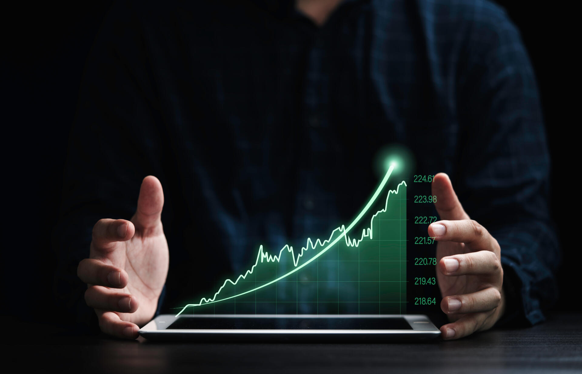 Ein Mann hält seine Hände neben ein Tablet. Darüber ist in der Luft eine aufsteigende Statistik